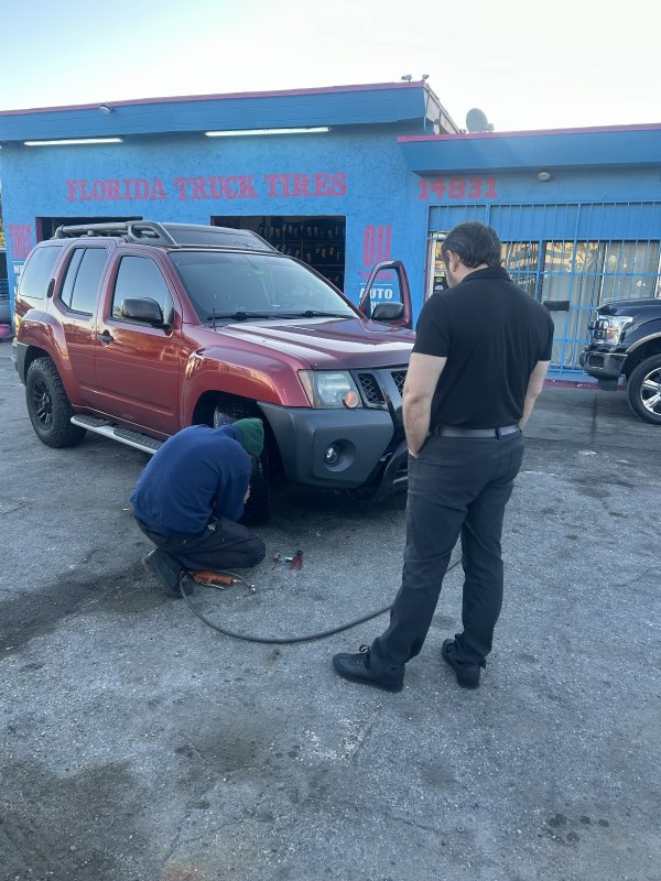 Technician changing a tire on an SUV outside the Florida Truck Tires shop
